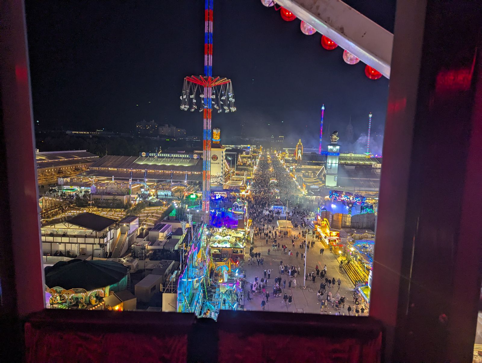The Oktoberfest grounds lit up at night, seen from a Ferris wheel gondola