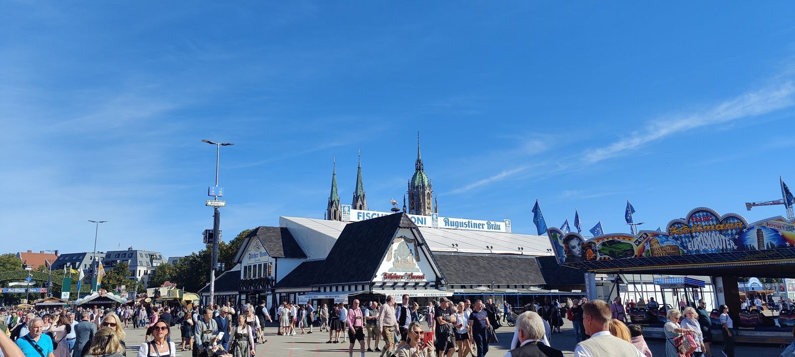 Sunny midweek panorama across the Oktoberfest grounds with tents and the Paulskirche spires behind