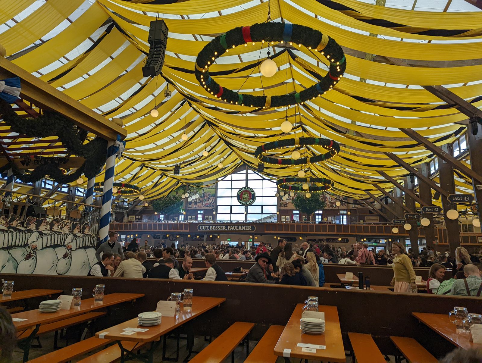 Paulaner Festzelt half empty just after opening on opening day, yellow canopy and ring chandeliers