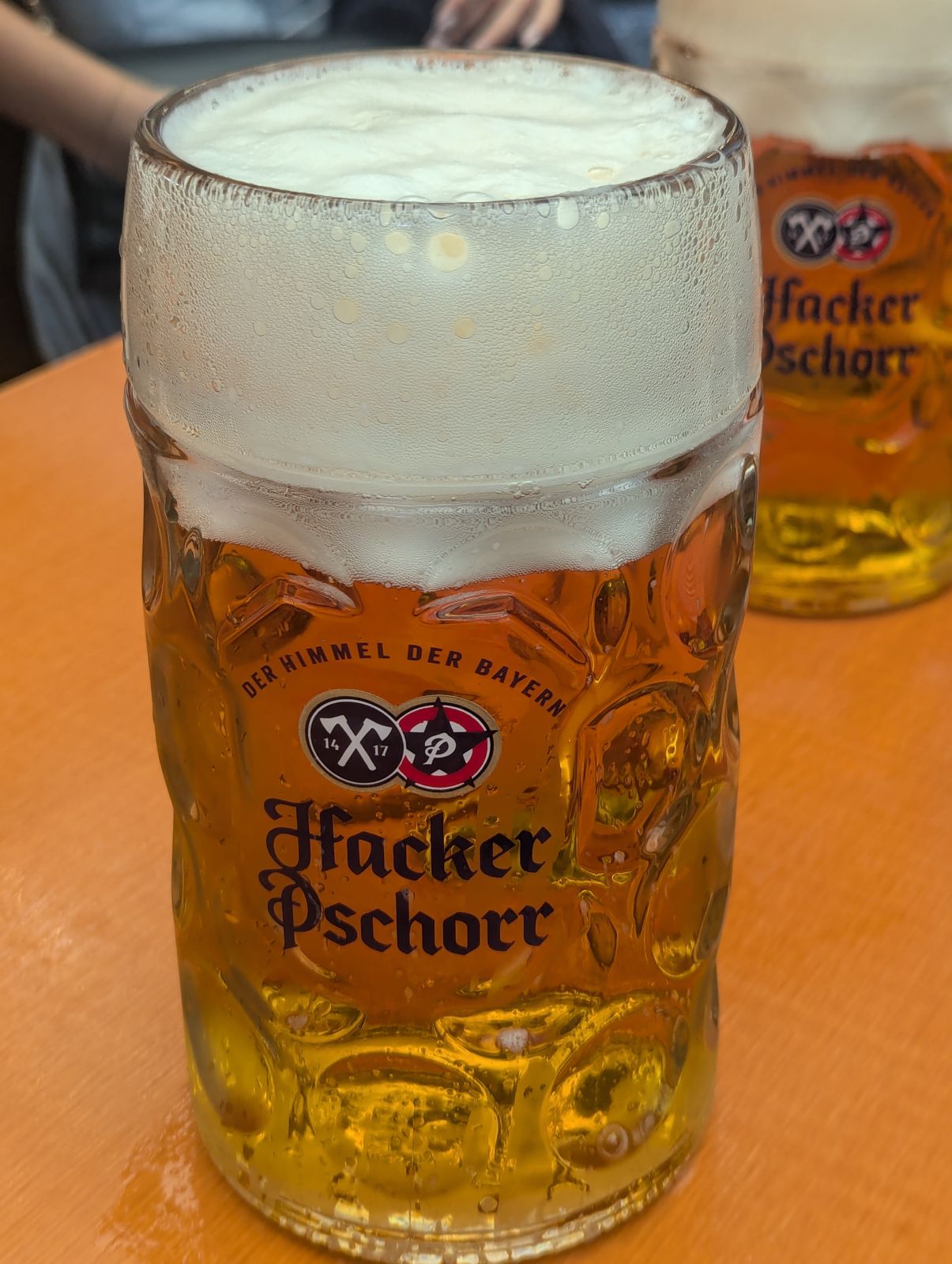 A full one-litre Hacker-Pschorr Maß with a foam head on a tent table