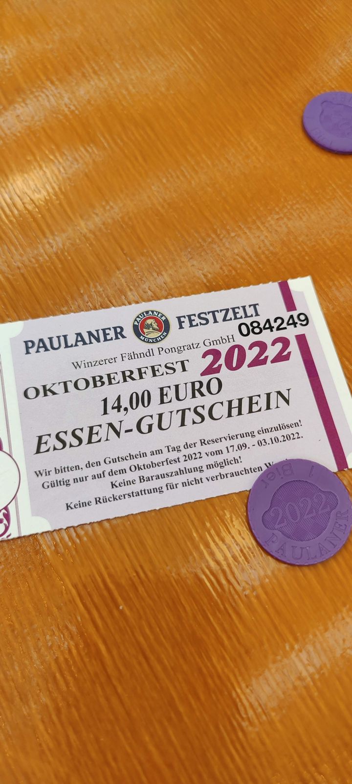 A €14 Paulaner Festzelt food voucher and a purple beer token from 2022