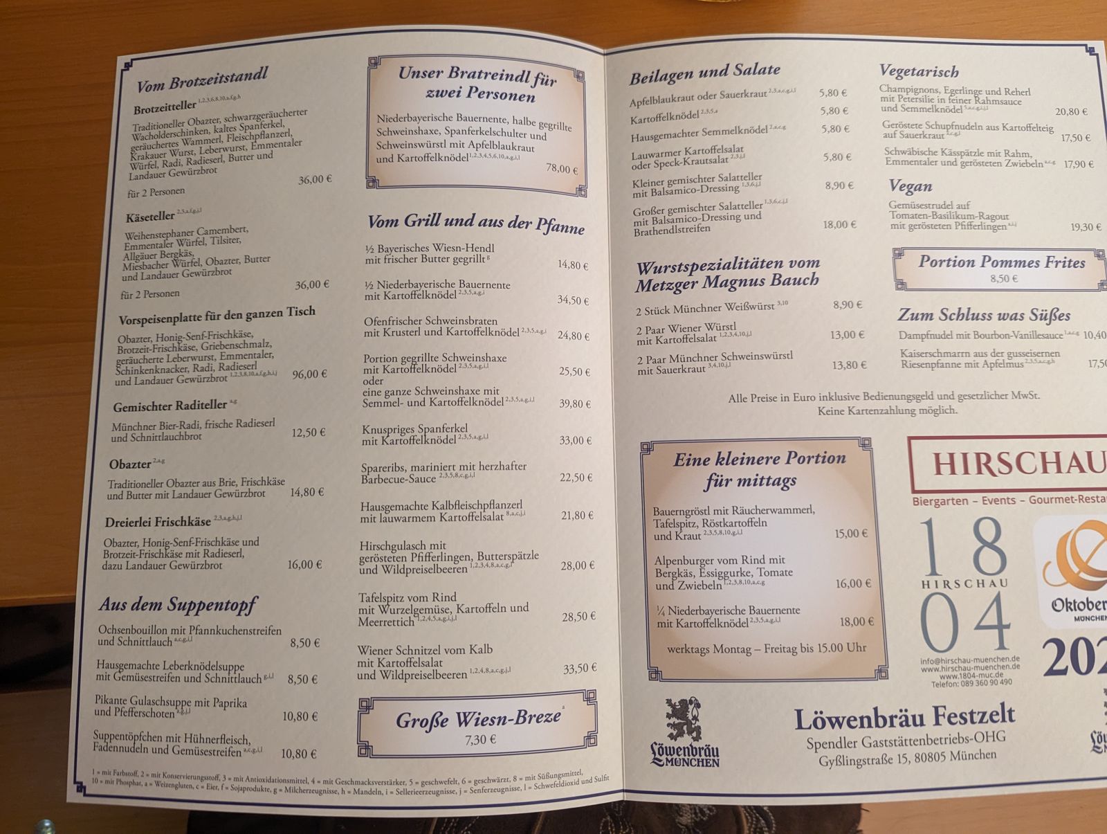 Löwenbräu Festzelt menu from 2023 listing half a Hendl at €14.80, Schweinshaxe at €25.50 and a Wiesn Breze at €7.30