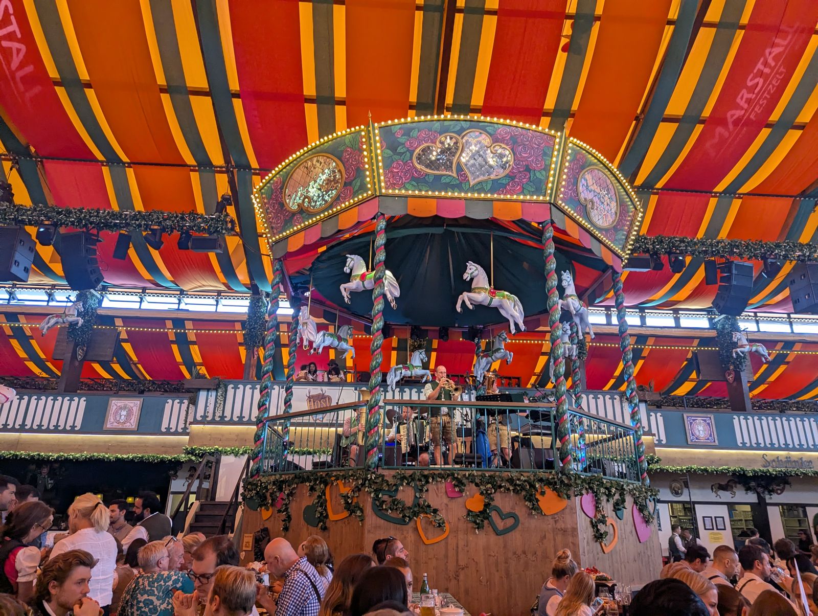 Marstall tent interior with an orange-striped canopy and the carousel-horse bandstand