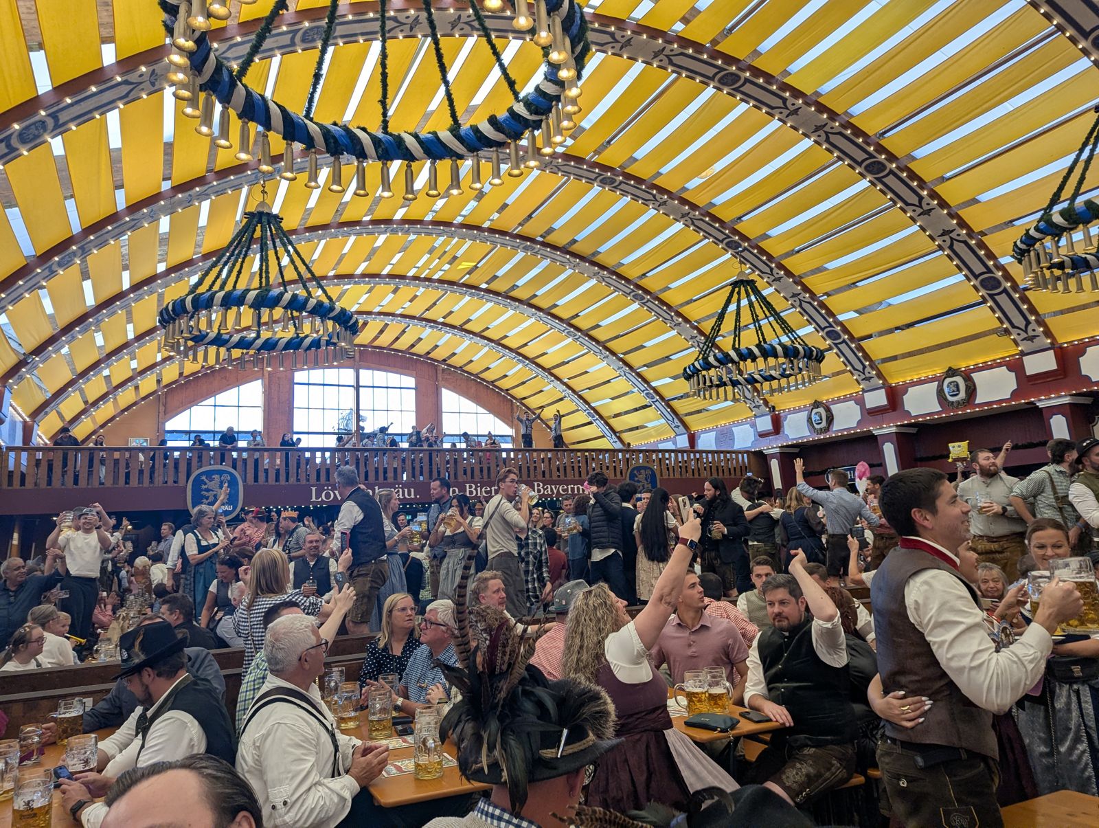 Löwenbräu-Festzelt interior with a yellow arched roof and blue-and-white chandelier rings