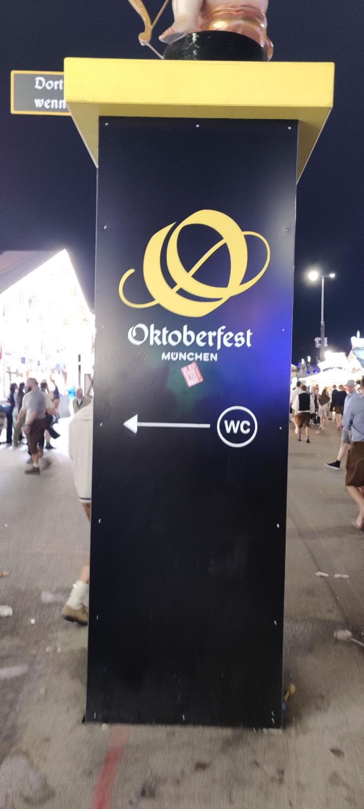 Official Oktoberfest wayfinding sign at night with an arrow to the toilets