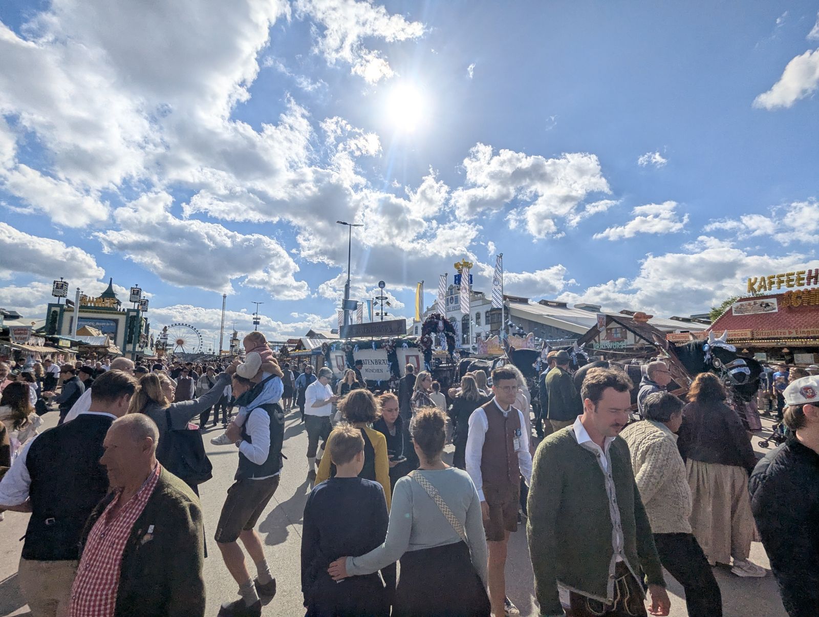 Sunny Oktoberfest avenue with visitors in lederhosen and dirndl